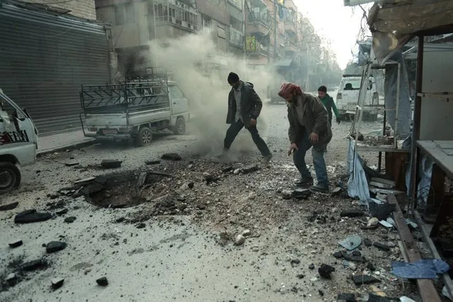 Syrian men check the damage following Syrian government shelling on the town of Douma in the rebel-held enclave of Eastern Ghouta on the eastern outskirts of the capital Damascus on March 10, 2018. Syrian regime forces cut off the largest town in Eastern Ghouta from the rest of the opposition enclave in a blow to beleaguered rebels defending their last bastion near Damascus. Government troops and allied militia have recaptured half of the besieged region in a blistering assault launched on February 18 that has left nearly 1,000 civilians dead and prompted global outcry. (Photo by Hamza Al-Ajweh/AFP Photo)