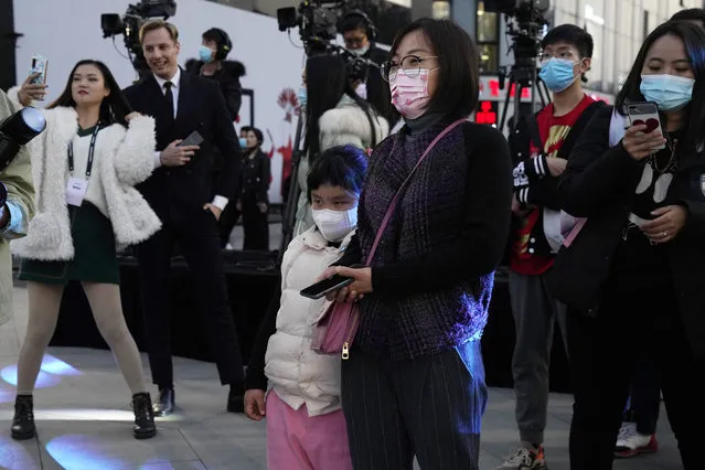 Residents wearing masks to protect themselves from the coronavirus watch a promotion event involving foreign models in Beijing on Friday, November 6, 2020. China has temporarily banned the entry of foreigners from at least eight countries as COVID-19 cases rise in Europe and elsewhere, as part of its strict measures that have largely ended domestic transmission of the virus. (Photo by Ng Han Guan/AP Photo)