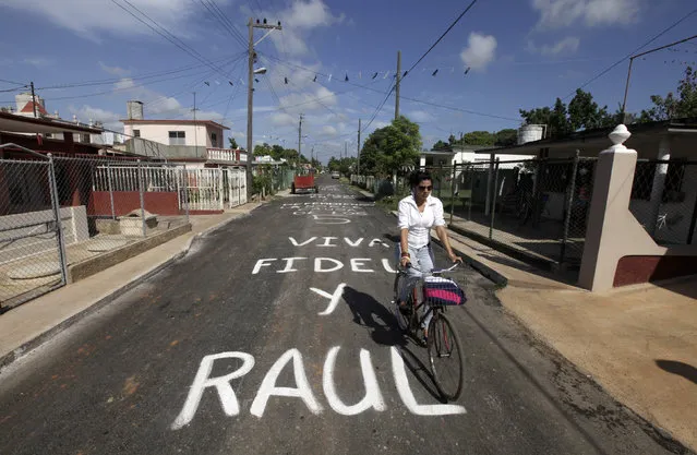 A woman rides her bicycle on a road that reads “Long live Fidel and Raul” in Artemisa province, near Havana July 25, 2014. (Photo by Enrique de la Osa/Reuters)