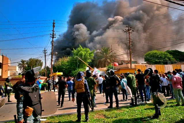 Smoke rises as the headquarters of Kurdish Democratic Party burn during a protest by pro-Iranian militiamen and their supporters in Baghdad, Iraq, Saturday, October 17, 2020. Tens of supporters of the Popular Mobilization Forces torch the headquarters, in response to televised comments by a senior Kurdish government official calling for the ouster of militias from the heavily fortified Green Zone. The Popular Mobilization Forces is an array of militia groups, some with links to Iran, formed to fight the Islamic State group in 2014. (Photo by Khalid Mohammed/AP Photo)