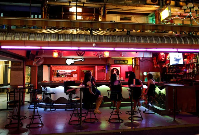 Women sit inside a bar in a red light district in Bangkok, Thailand, October 14, 2016, after it closed down temporarily following the death Thursday of Thailand's 88-year-old King Bhumibol Adulyadej, who was the world's longest reigning monarch. Concerts and colossal beach parties in Thailand have been canceled and many seedy go-go bars are closed as the death of revered King Bhumibol plunges this Southeast Asian nation into an unprecedented period of mourning. (Photo by Issei Kato/Reuters)