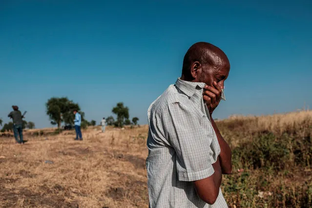 This photograph taken on November 21, 2020 shows a man reacting as he stands near a ditch in the outskirts of Mai Kadra, Ethiopia, that is filled with more than 20 bodies of victims that were allegedly killed in a massacre on November 9, 2020. A local youth group aided by police and militia killed at least 600 people in a “rampage” during the first week of fighting in Ethiopia's northern Tigray region, the national rights watchdog said on November 24, 2020. (Photo by Eduardo Soteras/AFP Photo)