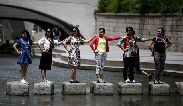 Visitors pose for a souvenir photo in a hot day at the Cheonggye stream in Seoul, South Korea, Wednesday, June 29, 2016. South Korean Meteorological Administration forecasted the temperature would go up to 31 degrees Celsius (87.8 degrees Fahrenheit) in Seoul during the day. (Photo by Lee Jin-man/AP Photo)