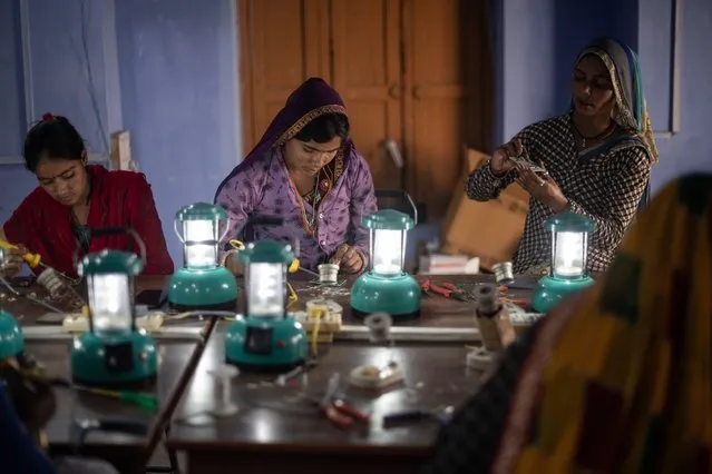 Indian villagers Dhanu (L), 21, Choti (C), 22, and Anita Devi, 35, assemble solar lamps in a class held as part of the Barefoot Solar Project to bring solar powered lighting to rural areas on March 25, 2023 in Solawata, India. The college focuses on expanding access to electricity to help reduce poverty in rural and marginalised communities, training women to make and install solar lamps and lighting systems to bring clean solar energy to remote villages. (Photo by Rebecca Conway/Getty Images)