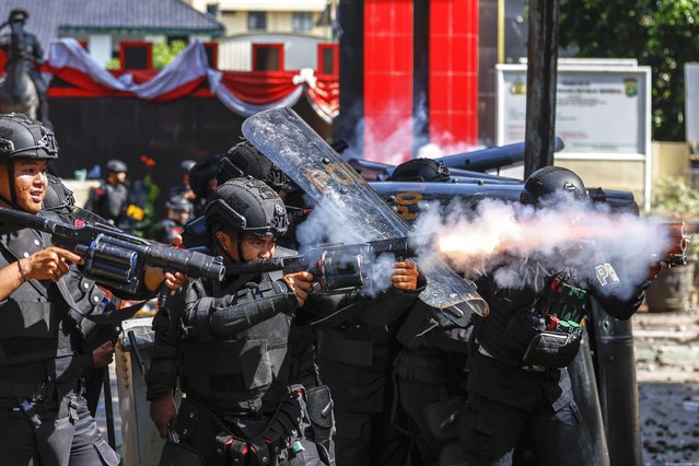 Protesters run as tear gas canisters explode during clashes with police outside the Mobile Brigade police headquarters in Jakarta, Indonesia, 29 August 2025. Hundreds of protesters and motorbike-hailing drivers staged a protest following the death of a motorbike-hailing driver during an earlier demonstration against the housing allowance for members of parliament. (Photo by Mast Irham/EPA)