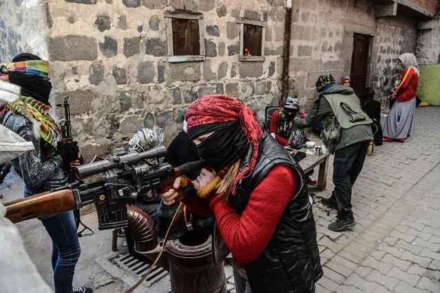 Armed Kurdish women millitants, man a barricade, on November 18, 2015 in the Sur district of Diyarbakir. Tensions rose when pro-Kurdish MP Leyla Zana began her oath with "Biji Asiti", or "Long live peace" in Kurdish. The phrase triggered a storm that recalled her memorable swearing-in 24 years ago when she also spoke the language that was then still taboo in public. (Photo by Ilyas Akengin/AFP Photo)