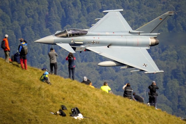 Aviation buffs observe an Eurofighter Typhoon German Airforce aircraft fly by during a show of military and acrobatic aviation near the Heroes Cross on Caraiman Peak on top of Bucegi mountains, in Busteni, Romania, Tuesday, August 26, 2025. (Photo by  Vadim Ghirda/AP Photo)