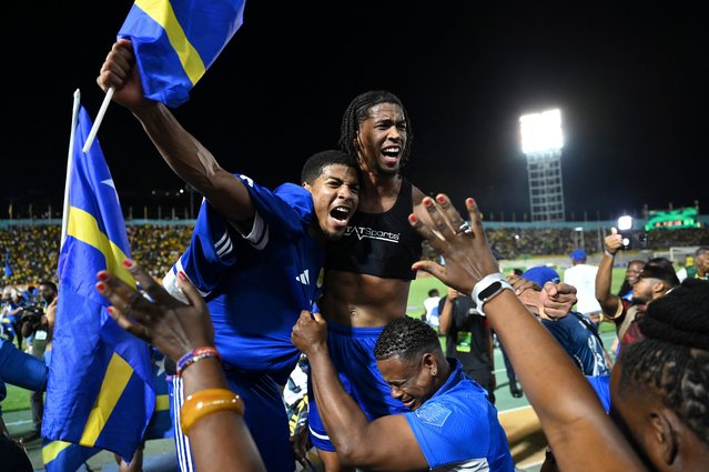 Curaçao players and fans celebrate World Cup 2026 qualification after a 0-0 draw with Jamaica at the National Stadium in Kingston, Jamaica on November 18, 2025. The tiny Caribbean nation of Curacao became the smallest country ever to qualify for the World Cup on November 18 as Haiti booked their return to the tournament for the first time in 52 years along with Panama. A nerve-shredding finale to the CONCACAF qualifying campaign saw Curacao -- with a population of just 156,000 -- squeeze into next year's finals in the United States, Canada and Mexico with a 0-0 draw against Jamaica in Kingston. (Photo by Ricardo Makyn/AFP Photo)