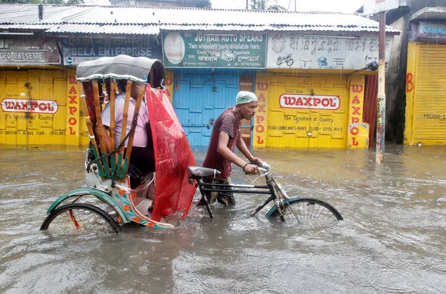 A man paddles his rickshaw as he helps a passenger wade through a water-logged street during heavy rains in Agartala May 18, 2018. (Photo by Jayanta Dey/Reuters)