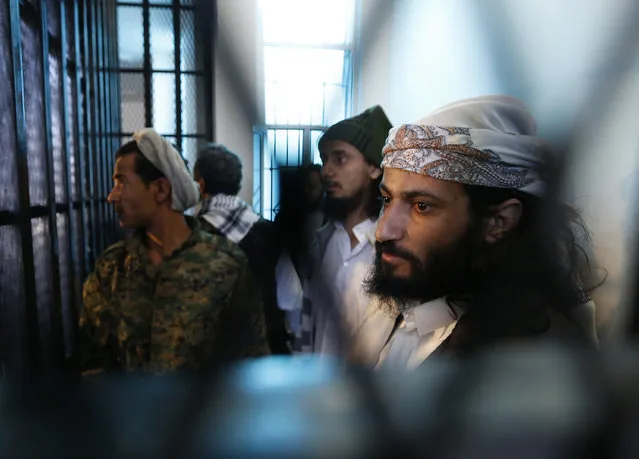 Defendants look out from behind bars as they stand in the holding cell of the state security court in Sanaa December 2, 2014. (Photo by Khaled Abdullah/Reuters)