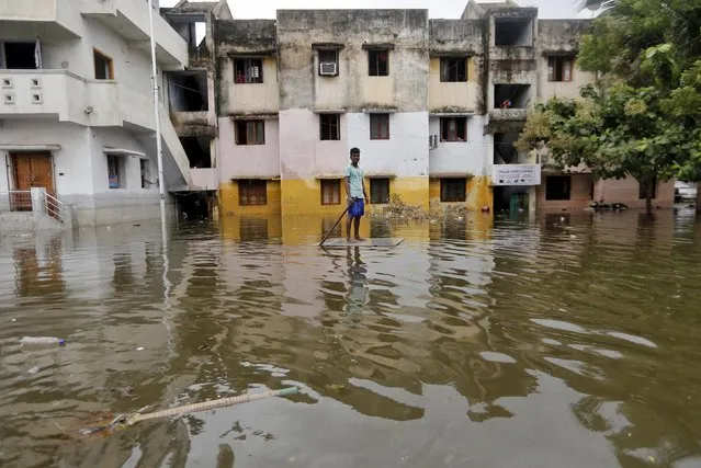 A man uses a board to float through a flooded street to reach to a market place in Chennai, India, December 5, 2015. (Photo by Anindito Mukherjee/Reuters)
