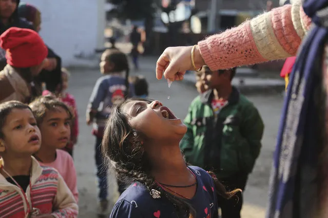 A health worker administers polio drops to children at a government school in a slum area in Jammu, India, Sunday, January 31, 2021. Polio is a highly infectious disease that spreads in contaminated water or food and usually strikes children under 5. (Photo by Channi Anand/AP Photo)