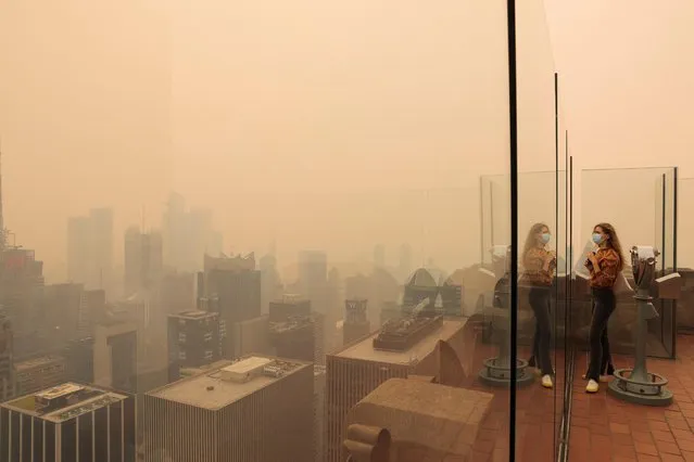 A person looks out from the top of the Rockefeller Center, as haze and smoke caused by wildfires in Canada hang over the Manhattan skyline, in New York City, New York, U.S., June 7, 2023. (Photo by Andrew Kelly/Reuters)