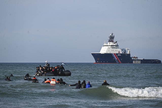 Migrants swim to board a smugglers' boat in order to attempt crossing the English channel off the beach of Audresselles, northern France on October 25, 2024. Two people died while attempting to cross the Channel from northern France to Britain early October 23, 2024, French authorities said, adding that around 50 people more had been rescued from a sinking boat. (Photo by Bernard Barron/AFP Photo)