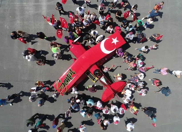 People gather to celebrate Semin Ozturk, Turkey's first professional female aerobatic pilot after she performed a demonstration flight with her “Pitts S2-B” plane that has Lycoming engine with 360 horsepower, in Eskisehir, Turkey on July 01, 2018. A 27-year-old aerobatic pilot Semin experienced her first aerobatic flight performing when she was 12 years old with her father Ali Ismet Ozturk who is also an aerobatic pilot. On 19 September 2015, she realized her first airshow at Sivrihisar General Aviation Center. Ozturk will attend the Aeromania Airshow which will take place between July 14-15. The Aeromania Airshow to host 35 aerobatic pilots from many countries. (Photo by Ali Atmaca/Anadolu Agency/Getty Images)
