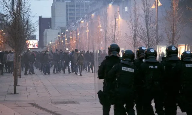 Protesters throw stones toward police in riot gear guarding the government building in Kosovo, Pristina on Saturday, January 24, 2015. Kosovo police in riot gear used tear gas to disperse a stone throwing crowd during a demonstration by several thousand people demanding that the government dismiss one of its three Serb ministers, accusing him of insulting the ethnic Albanian majority. (Photo by Visar Kryeziu/AP Photo)