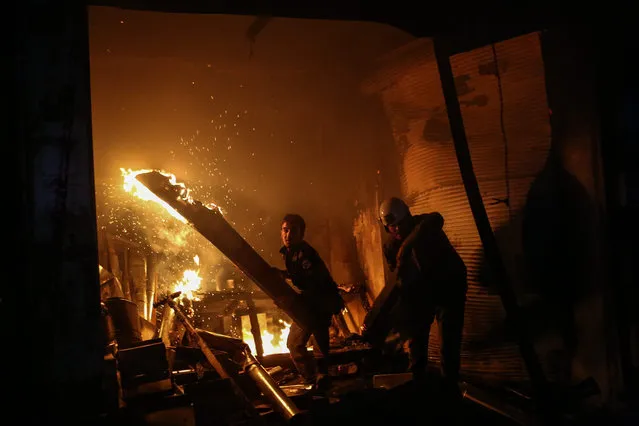 Volunteers of the Syrian Civil Defense, also known as the White Helmets, carry large pieces of burned wood as they try to extinguish a fire after a bombing in Douma, on the outskirts of Damascus, Syria, late 17 November 2016. According to local reports, at least six people were killed and 30 injured in several bombings mostly throughout the night. (Photo by  Mohammed Badra/EPA)