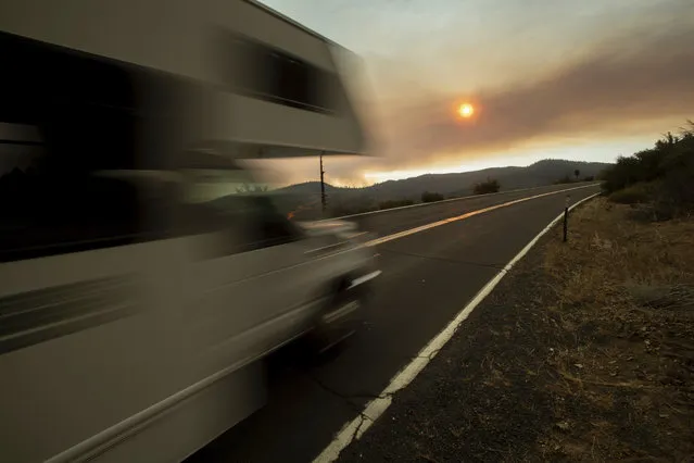 A recreational vehicle drives out of Yosemite Valley in Yosemite National Park, Calif., on Tuesday, July 24, 2018, as smoke from the Ferguson Fire fills the sky. Parts of the park, including Yosemite Valley, will close Wednesday as firefighters work to stop the blaze. (Photo by Noah Berger/AP Photo)