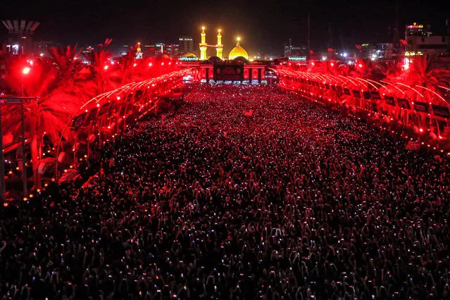 Shiite Muslim devotees gather during the flag-changing ceremony at the shrines of Imam Hussein and Imam Abbas in Iraq's central shrine city of Karbala on July 18, 2023, on the first night of the Muslim month of Muharram and the first day of the Islamic New Year. (Photo by Mohammed Sawaf/AFP Photo)