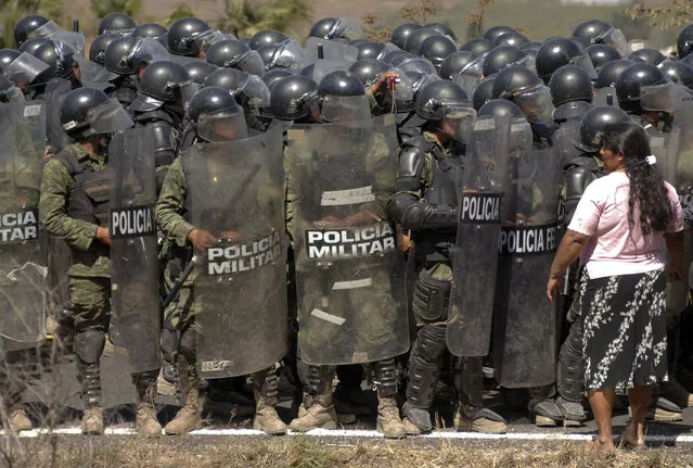 A woman stands in front of Mexican army military police in a neighborhood in the city of Chilpancingo, Mexico, Friday, February 6, 2015. Residents were blocking a road to protest the detention of two members of their community and battled with military police dressed in riot gear who tried to clear the road. At least three people were detained. (Photo by Alejandrino Gonzalez/AP Photo)