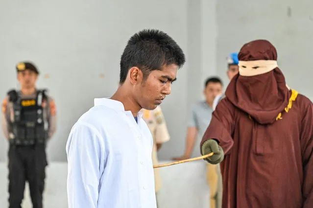 A man is caned by a member of the Sharia police as punishment for consuming alcohol, in Banda Aceh on August 2, 2023. Aceh is the only province in the world's most populous Muslim-majority country that imposes sharia law and people can be flogged for a range of offences – from gambling, to drinking alcohol to having gay sеx or relations outside of marriage. (Photo by Chaideer Mahyuddin/AFP Photo)