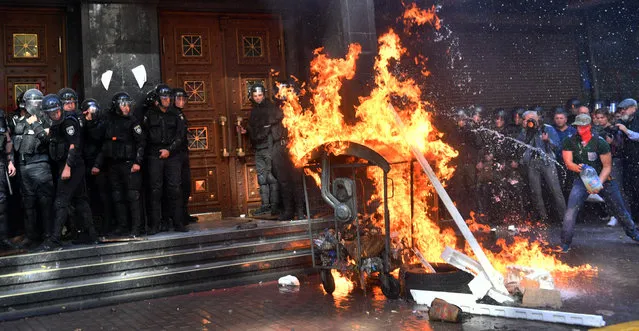 Activists of Ukrainian far-right groups burn a fire during their clashing with riot police in front of the Prosecutor General's Office in Kiev on September 17, 2018 as the Ukrainian authorities extradited a Russian citizen wanted by Moscow as a suspected Islamic State fighter. Dozens of protesters, mostly from Ukraine's far-right groups, blocked the entrance to the building of prosecutor general's office with a trash can and set it on fire and then tried to storm it with a demand to sack the deputy prosecutor general who signed the permission to extradite Timur Tumgoyev, AFP photographer reports. (Photo by Sergei Supinsky/AFP Photo)
