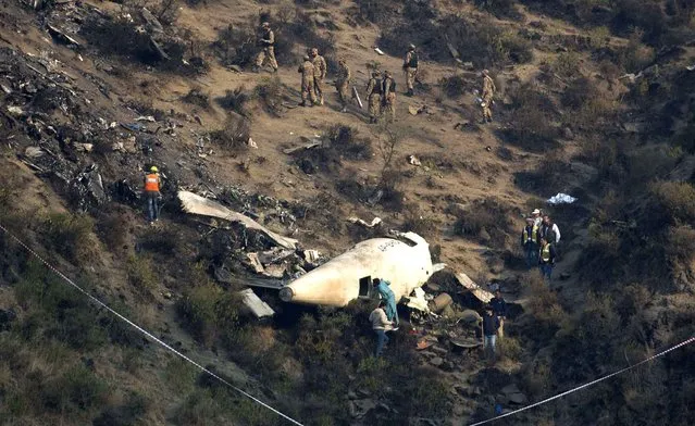 Pakistani investigators examine the wreckage of a passenger plane crashed in the village of Gug, Pakistan Thursday, December 8, 2016. A Pakistani aviation spokesman says authorities have opened a probe into the plane crash in the country's northwest the previous day. (Photo by B.K. Bangash/AP Photo)