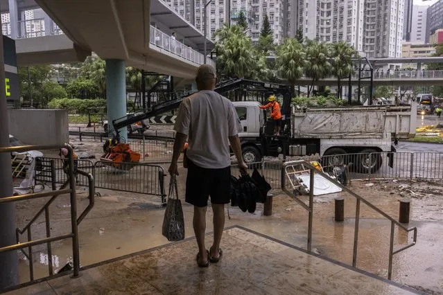 A pedestrian stands on a higher place near a flooded road following heavy rainstorms in Hong Kong, Friday, September 8, 2023. (Photo by Louise Delmotte/AP Photo)