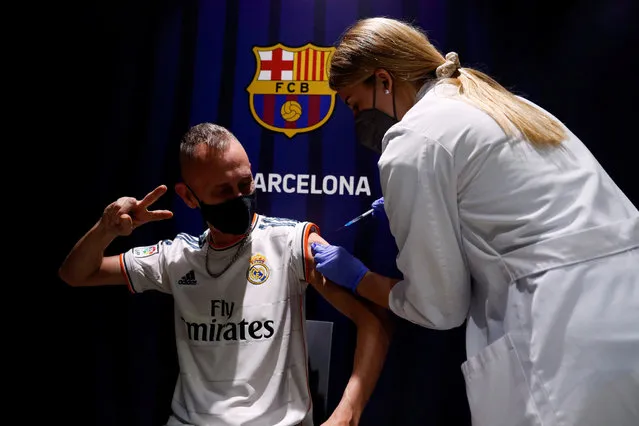 A man wearing a Real Madrid jersey receives a dose of Pfizer-BioNTech vaccine against the coronavirus disease (COVID-19) at soccer FC Barcelona's Camp Nou stadium, in Barcelona, Spain, May 27, 2021. (Photo by Albert Gea/Reuters)