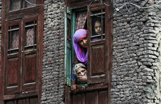Local residents look out from a window near the site were a gun battle took place between suspected militants and Indian government forces in downtown Srinagar on October 17, 2018. Two suspected militants and one security force personnel were killed during a gun battle according to officials said. (Photo by Tauseef Mustafa/AFP Photo)