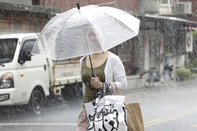 A woman holds an umbrella in heavy rain after Typhoon Saola moves away in Taipei, Taiwan, Thursday, August 31, 2023. (Photo by Chiang Ying-ying/AP Photo)