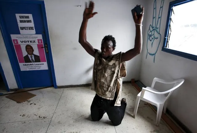 A man on his knees raises his hands inside an Ivorian Popular Front (FPI) office after being detained for suspected involvement in reprisal attacks on a local FPI office in Abidjan December 2, 2010. (Photo by Emmanuel Braun/Reuters)