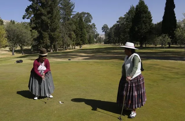 Aymara Indigenous women, Teresa Zarate, left, putts the ball while Martha Mamani watches her during the workers' tournament at the La Paz Golf Club of Mallasilla on the outskirts of La Paz, Bolivia, Monday, August 1, 2022. (Photo by Juan Karita/AP Photo)