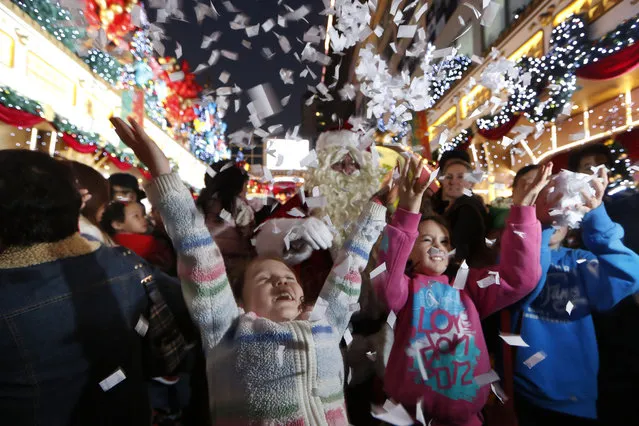 Visitors play with shredded papers with Christmas decorations to celebrate the festival season at a shopping mall in Hong Kong, Monday, December 23, 2013. (Photo by Kin Cheung/AP Photo)