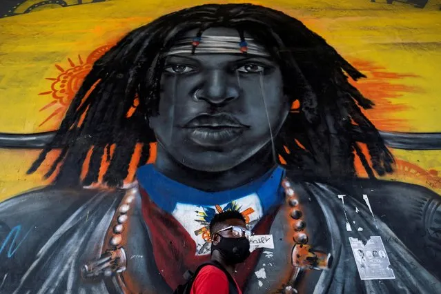 A man walks past a mural under an overpass in Port-au-Prince, Haiti on July 26, 2021. (Photo by Ricardo Arduengo/Reuters)