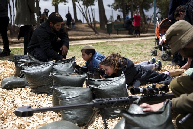 An Israeli girl looks through the sight of a weapon during a display of Israeli Defense Forces (IDF) equipment and abilities at the West Bank settlement of Kiryat Arba, April 23, 2015, during celebrations for Israel's Independence Day, marking the 67th anniversary of the creation of the state. (Photo by Ronen Zvulun/Reuters)