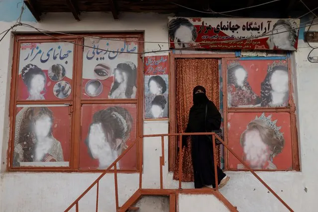 A woman wearing a niqab enters a beauty salon where the ads of women have been defaced by a shopkeeper in Kabul, Afghanistan on October 6, 2021. (Photo by Jorge Silva/Reuters)