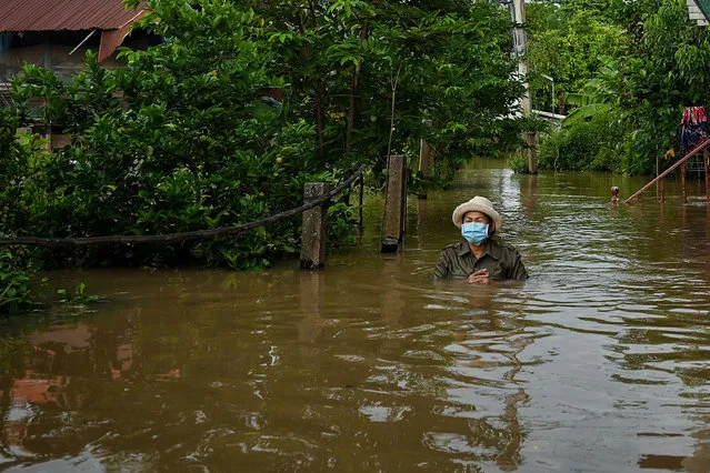 A resident wades through floodwaters outside her home in a neighborhood in the central Thai province of Ayutthaya on September 28, 2021, as tropical storm Dianmu caused flooding in 30 provinces across the country. (Photo by Lillian Suwanrumpha/AFP Photo)