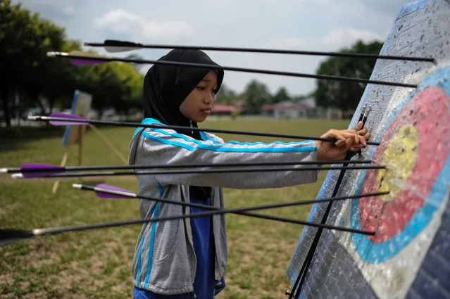 A Malaysian girl collects her arrows from a target board at an archery session during the school holidays in Hulu Langat, near Kuala Lumpur on March 16, 2016. Archery is a recreational and competitive sport popular among Malaysian youths during the school holiday season. (Photo by Mohd Rasfan/AFP Photo)