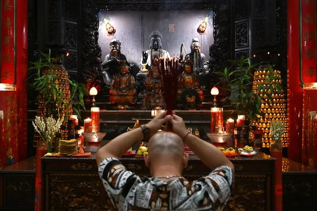 A man offer prayers at Satya Dharma temple in Denpasar on Indonesia's resort island of Bali on February 9, 2024, on the eve of the Lunar New Year of the Dragon which falls on February 10. (Photo by Sonny Tumbelaka/AFP Photo)