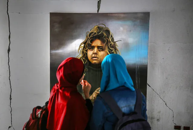 Palestinian artist Ali al-Jabali's paintings, composed of portraits of children, women, elders and young people, are being displayed at his exhibition named "Dreamers among the rubbles" on the walls of buildings, which have been damaged on Israeli attacks on July 2014, at al-Nasr neighborhood in Gaza City, Gaza on April 24, 2019. Ali al-Jabali has painted four walls and six oil paintings to draw attention to the difficulties of Palestinians in Gaza. (Photo by Mustafa Hassona/Anadolu Agency/Getty Images)