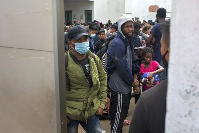 Migrants crowd into the patio at the Attorney Generals office after they were intercepted from inside cargo trailers driving on the highway, in Coatzacoalcos, Veracruz state, Mexico, Friday, November 19, 2021. About 500 migrants were riding in two cargo trucks when they were stopped and detained by the Criminal Investigation Agency and the National Immigration Institute, according to those two organizations. (Photo by Felix Marquez/AP Photo)