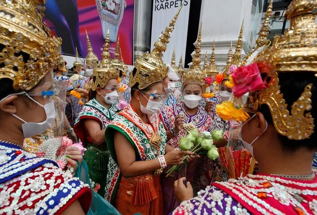 Thai dancers hold lotus flowers while performing for worshippers of the Lord Brahma statue during a ceremony held to mark the 65th establishment anniversary of the Erawan shrine in Bangkok, Thailand, 09 November 2021. The ceremony is held every year in the early morning of 09 November to worship the Lord Brahma statue to commemorate it being enshrined on 09 November 1956. (Photo by Narong Sangnak/EPA/EFE)