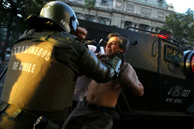 A riot policeman tries to detain a protester during a rally marking the anniversary of the death of union leader Juan Pablo Jimenez, in Santiago, Chile February 21, 2017. (Photo by Ivan Alvarado/Reuters)