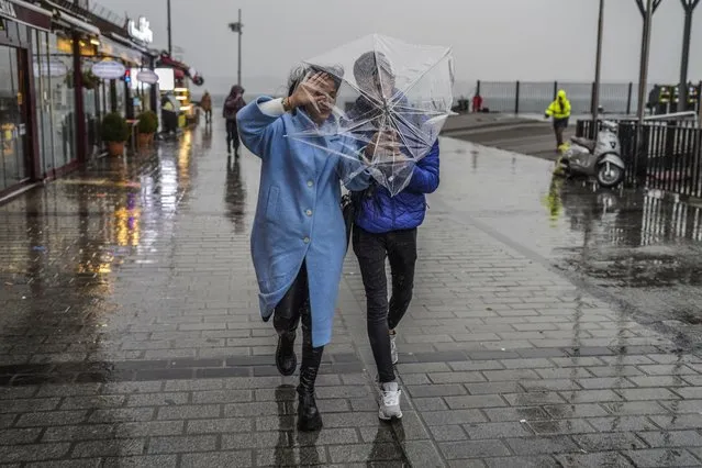A couple shelters against a heavy rain with an umbrella during a stormy day in Istanbul, Turkey, Monday, November 29, 2021. A powerful storm pounded Istanbul and other parts of Turkey on Monday, killing at least four people and causing havoc in the city of 15 million people, reports said. (Photo by AP Photo/Stringer)