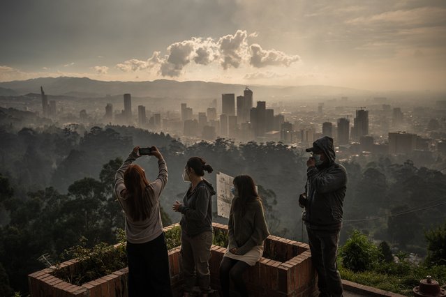 People take photos of the smoke over Bogota seen from El Paraiso neighborhood on January 26, 2024 in Bogota, Colombia. Over thirty forest fires were registered in Bogota and several regions of Colombia amid high temperature records due to the El Niño phenomenon. As the city faces a high level of air pollution, Colombia's President Petro has convened his ministers to create a unified command post and will ask for help from the United Nations to combat the fire hotspots. (Photo by Diego Cuevas/Getty Images)
