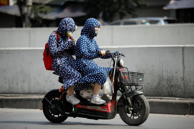 People wear clothing to protect them from the heat while riding along a street in Hanoi, Vietnam, 24 April 2019. North and central Vietnam was recently affected by extreme hot weather, with the highest temperatures reaching over 40 degrees Celcius, according to the National Centre for Hydro-meteorological Forecasting. (Photo by Luong Thai Linh/EPA/EFE)