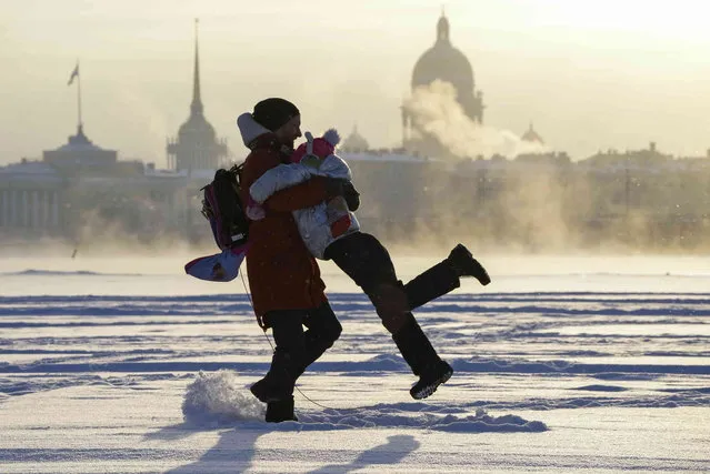 A man plays with his daughter on the ice of the Neva River in St. Petersburg, Russia, Tuesday, January 11, 2022. (Photo by Dmitri Lovetsky/AP Photo)