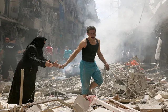 People walk amid the rubble of destroyed buildings following a reported air strike on the rebel-held neighbourhood of al-Kalasa in the northern Syrian city of Aleppo, on April 28, 2016. The death toll from an upsurge of fighting in Syria's second city Aleppo rose despite a plea by the UN envoy for the warring sides to respect a February ceasefire. (Photo by Ameer Alhalbi/AFP Photo)