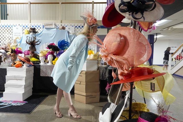 A woman tries on a decorative hat ahead of the Preakness Stakes horse race at Pimlico Race Course, Saturday, May 18, 2024, in Baltimore. (Photo by Julia Nikhinson/AP Photo)